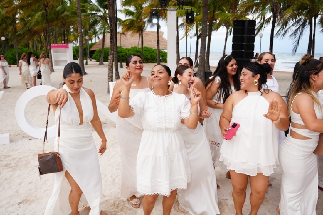 Asistentes vestidas de blanco en una fiesta en la playa